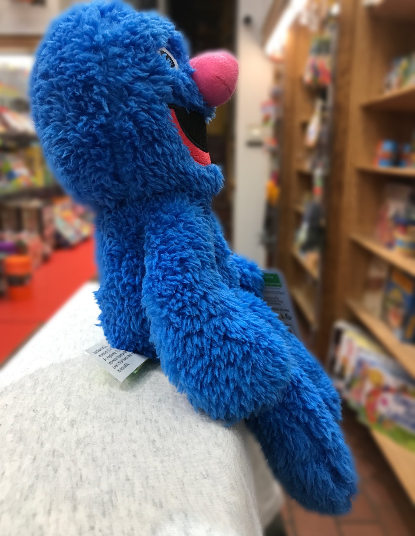 Soft blue Grover plush toy from Sesame Street by GUND, with long limbs and pink nose, displayed in a toy store setting
