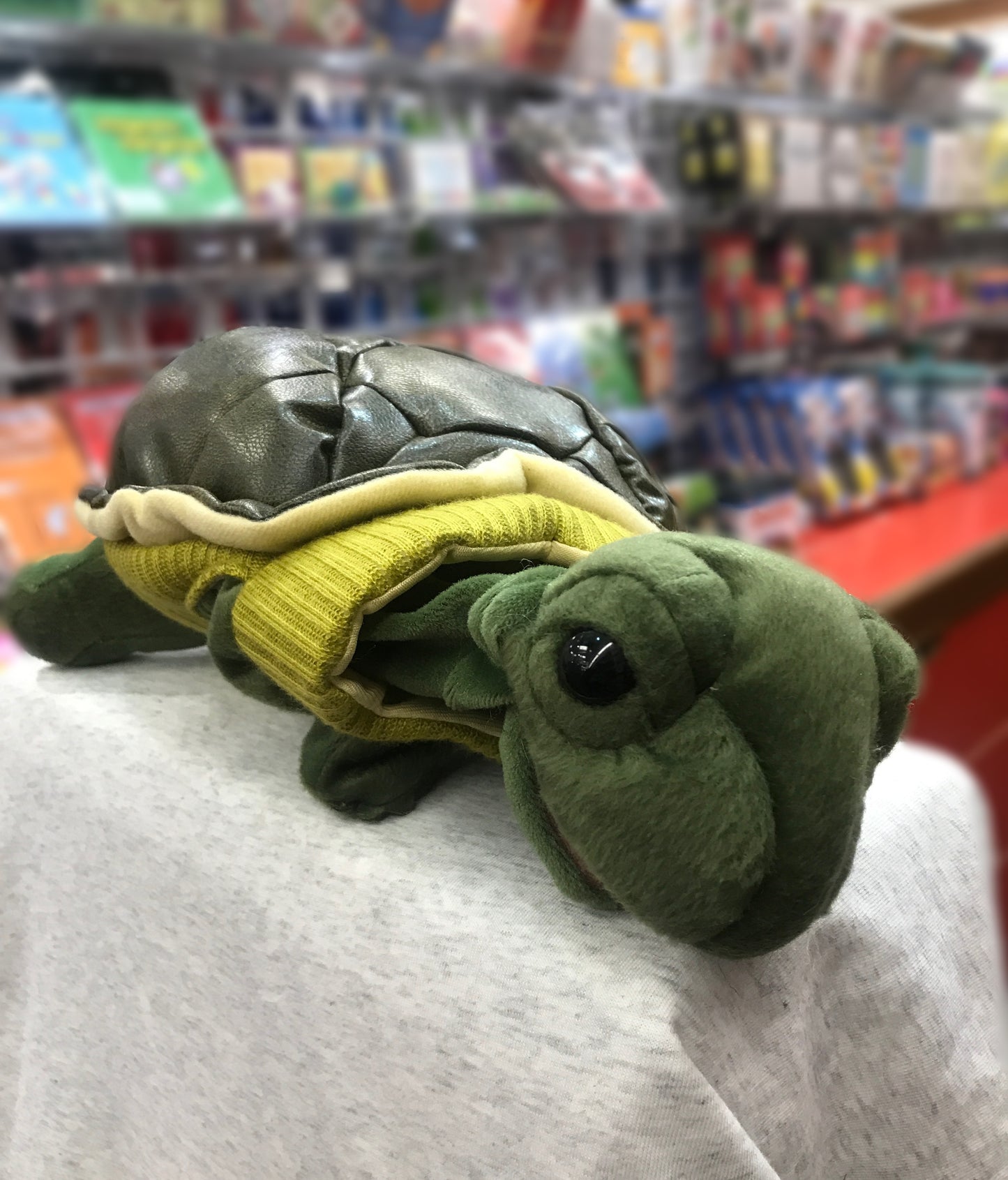 Adorable Folkmanis turtle puppet wearing yellow turtleneck sweater, displayed in toy store, perfect for imaginative play