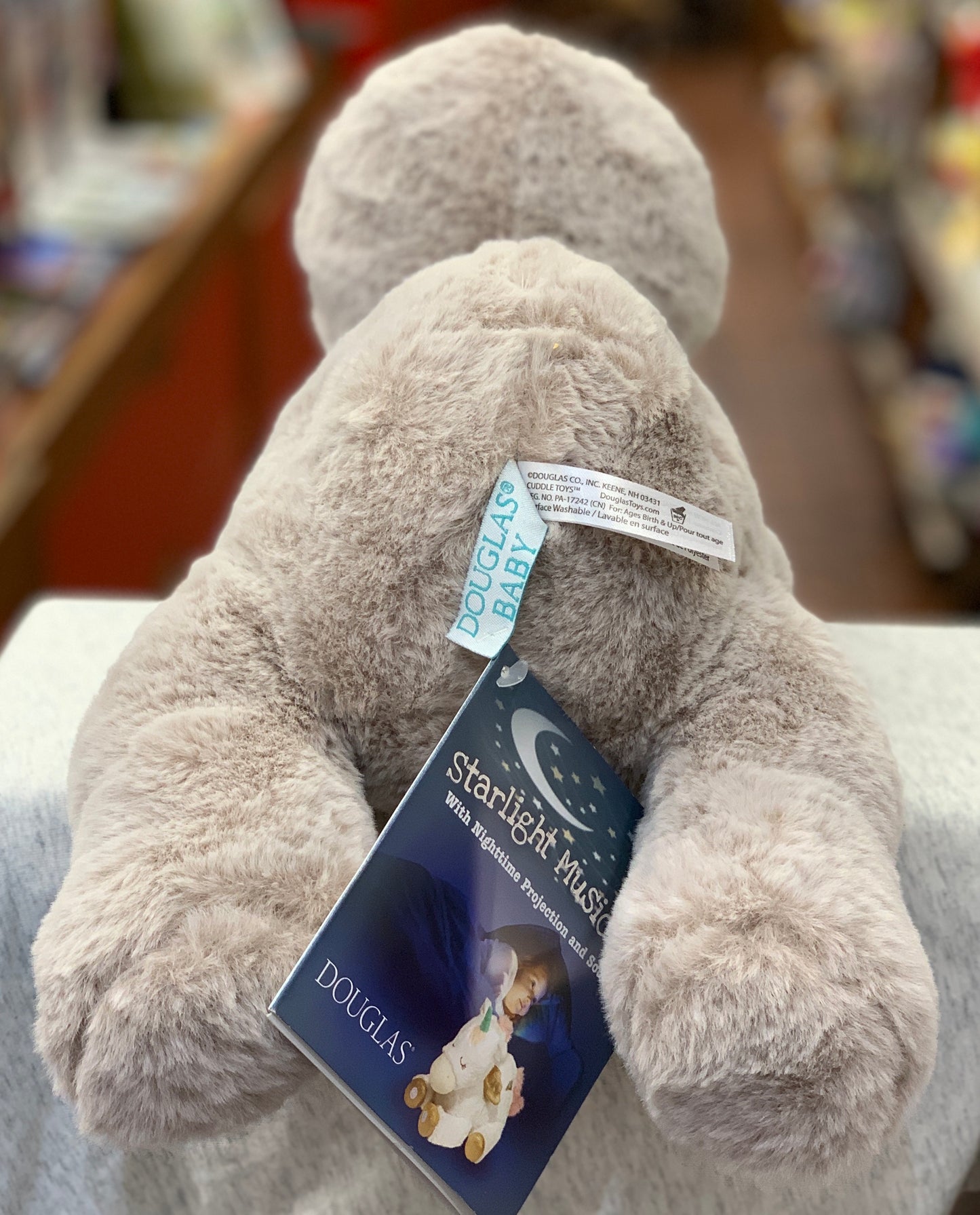 Soft plush sloth toy with Starlight Musical projector feature, showing product tag and packaging for Douglas Baby collection