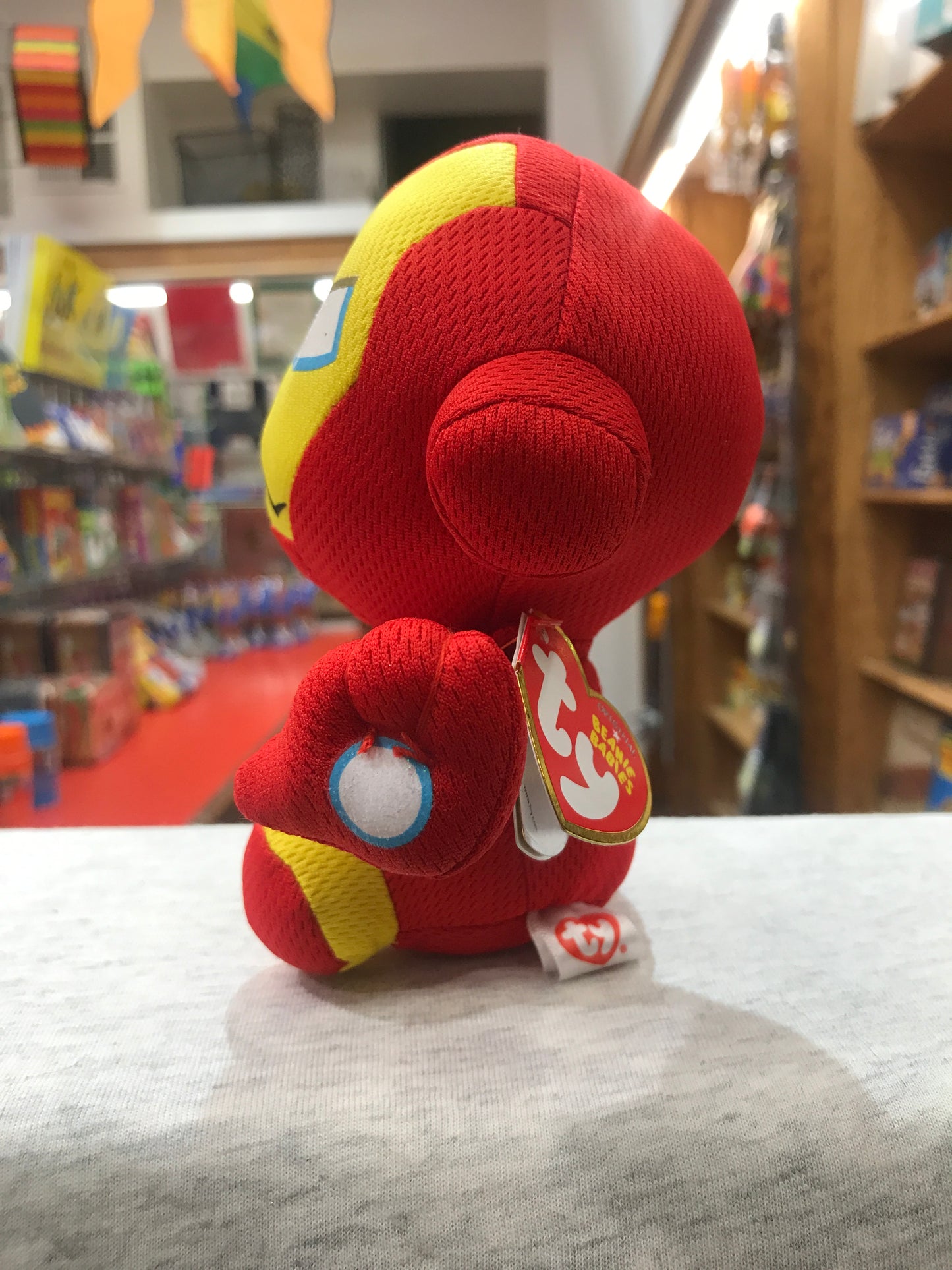 Ty Beanie Baby Iron Man plush toy, red and yellow, sitting on display in toy store, Marvel character collectible