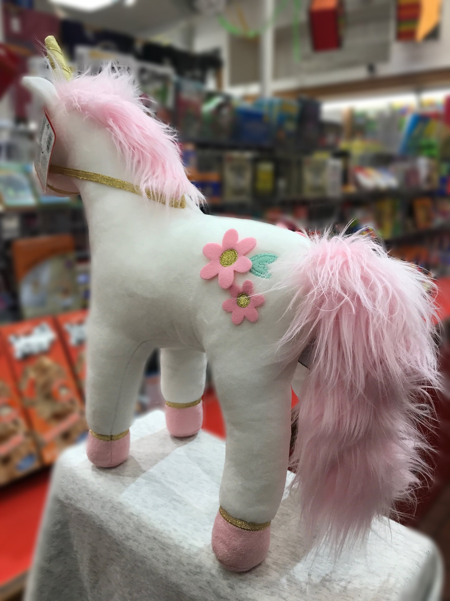 Gund Lilyrose unicorn plush with pink mane, gold horn, and floral accents on display in toy store