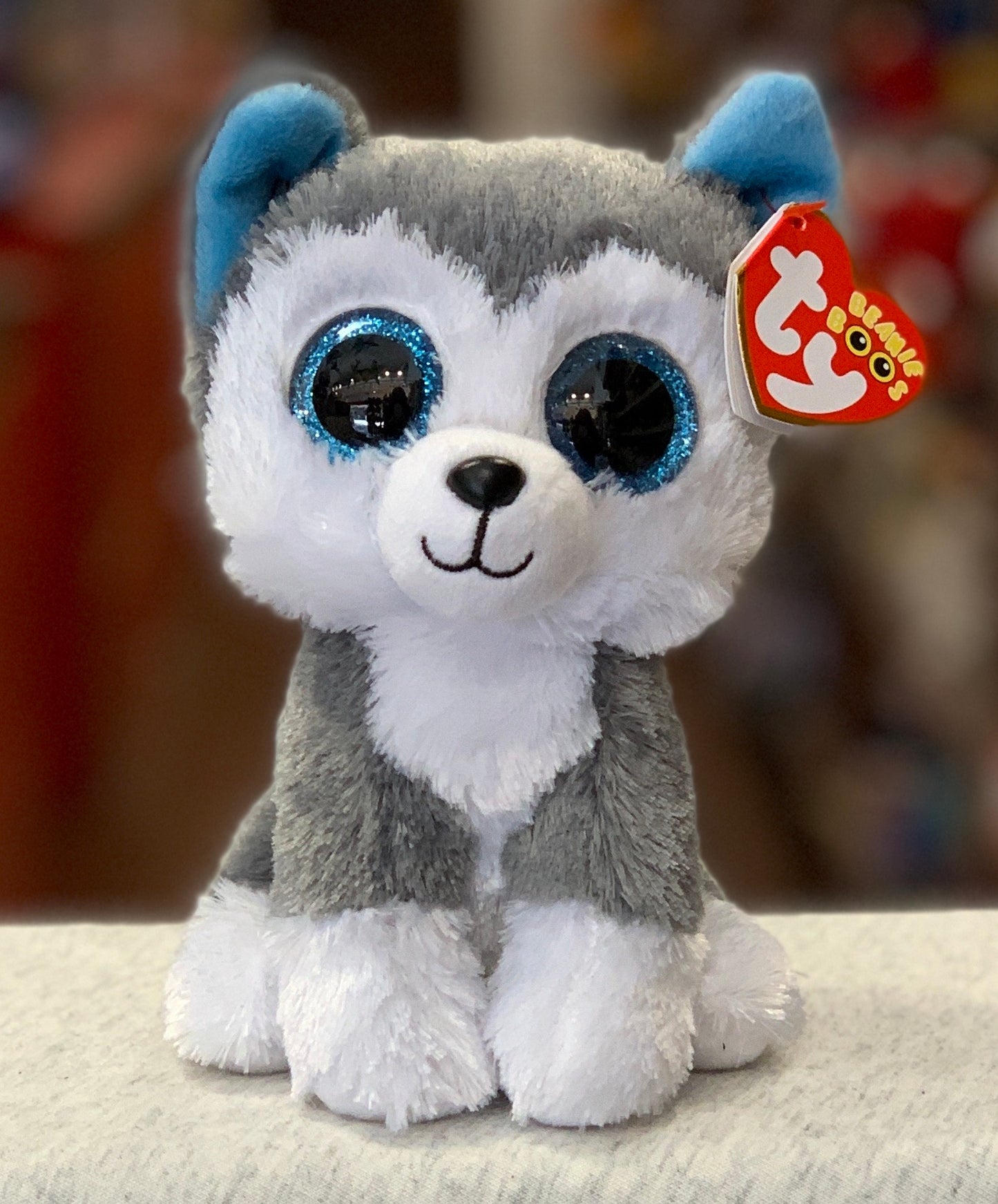 Ty Beanie Boo Slush husky plush toy with large blue glittery eyes, soft gray and white fur, and signature red heart tag