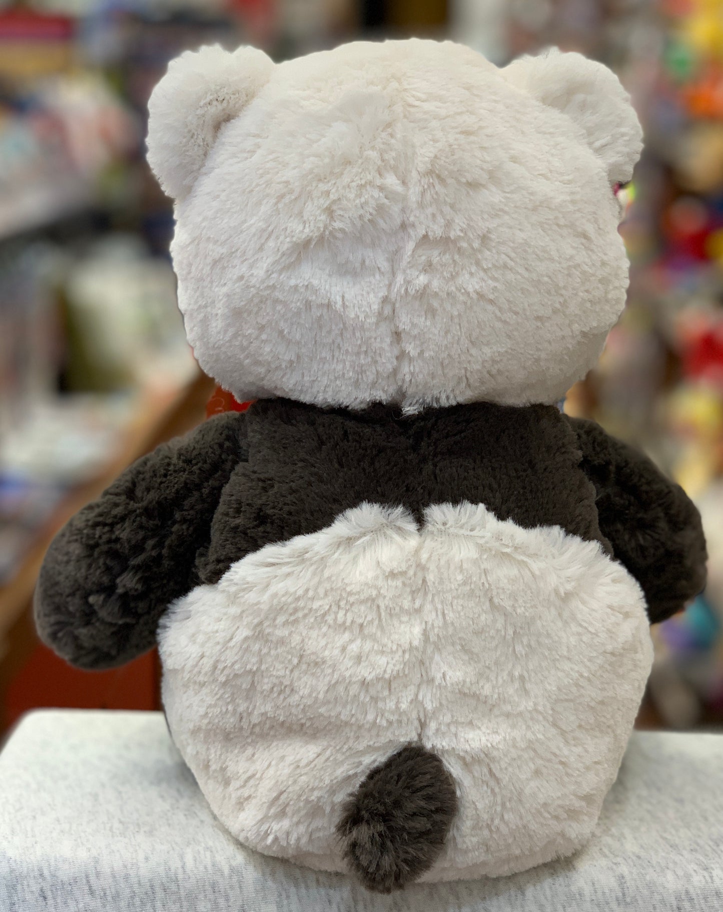 Cuddly panda plush toy with black and white fur, seen from behind, showcasing soft texture and adorable design