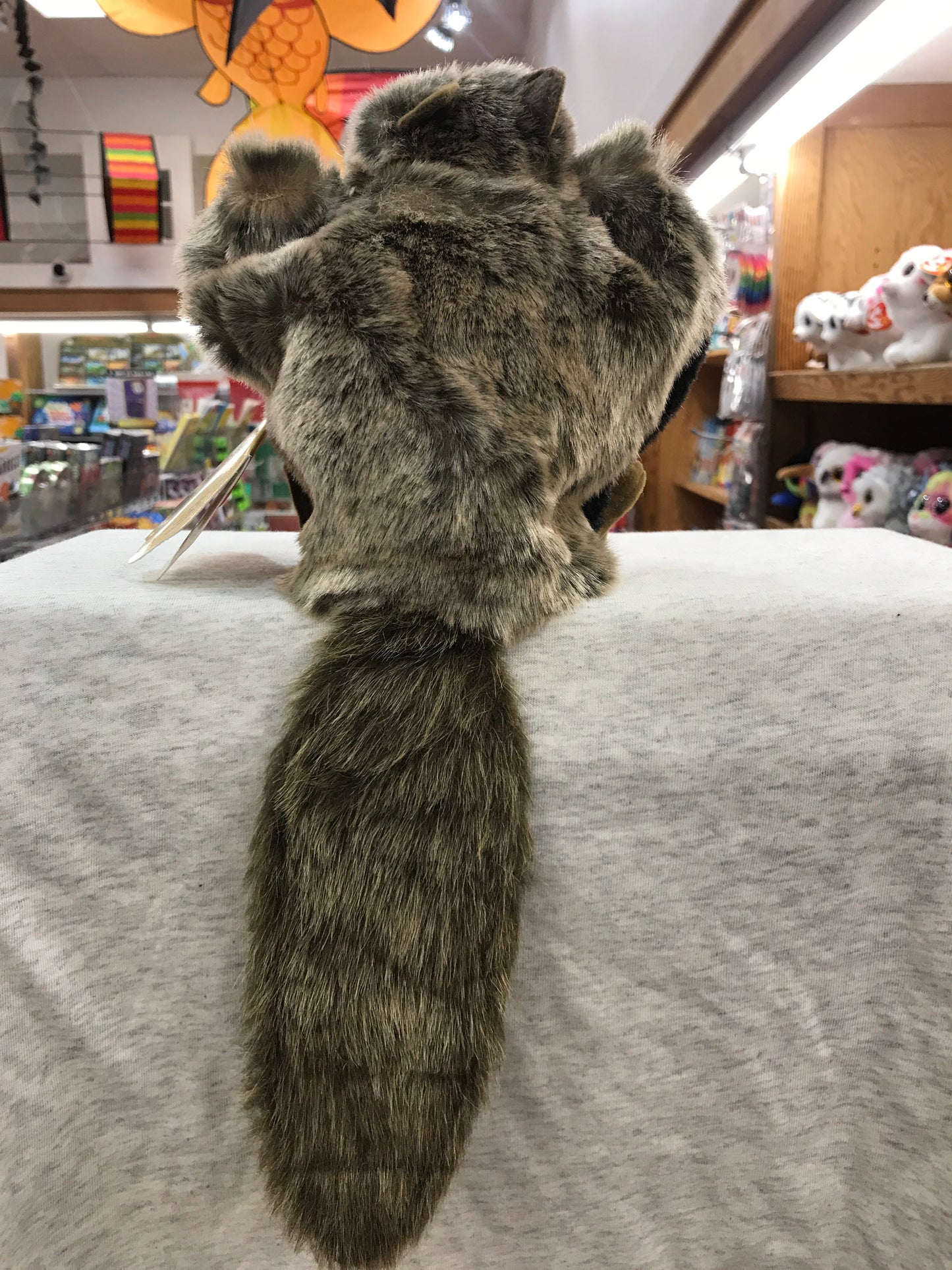 Soft, plush Folkmanis flying squirrel puppet with outstretched arms and bushy tail, displayed in toy store