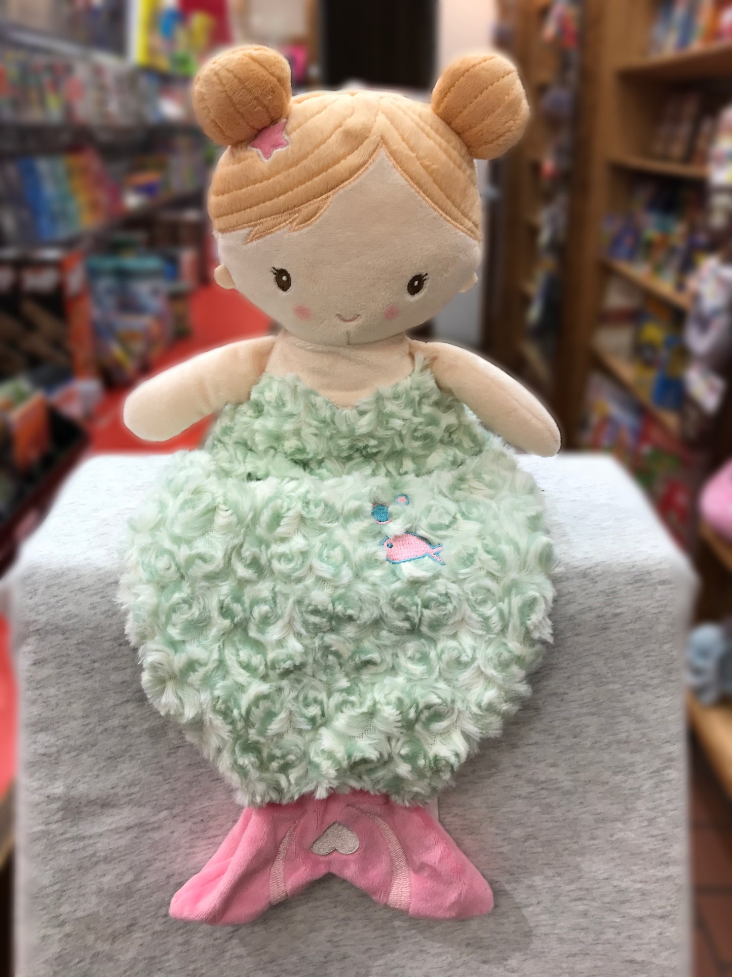Soft plush baby mermaid toy with blonde hair, green fluffy body, and pink tail, perfect for cuddling and playtime