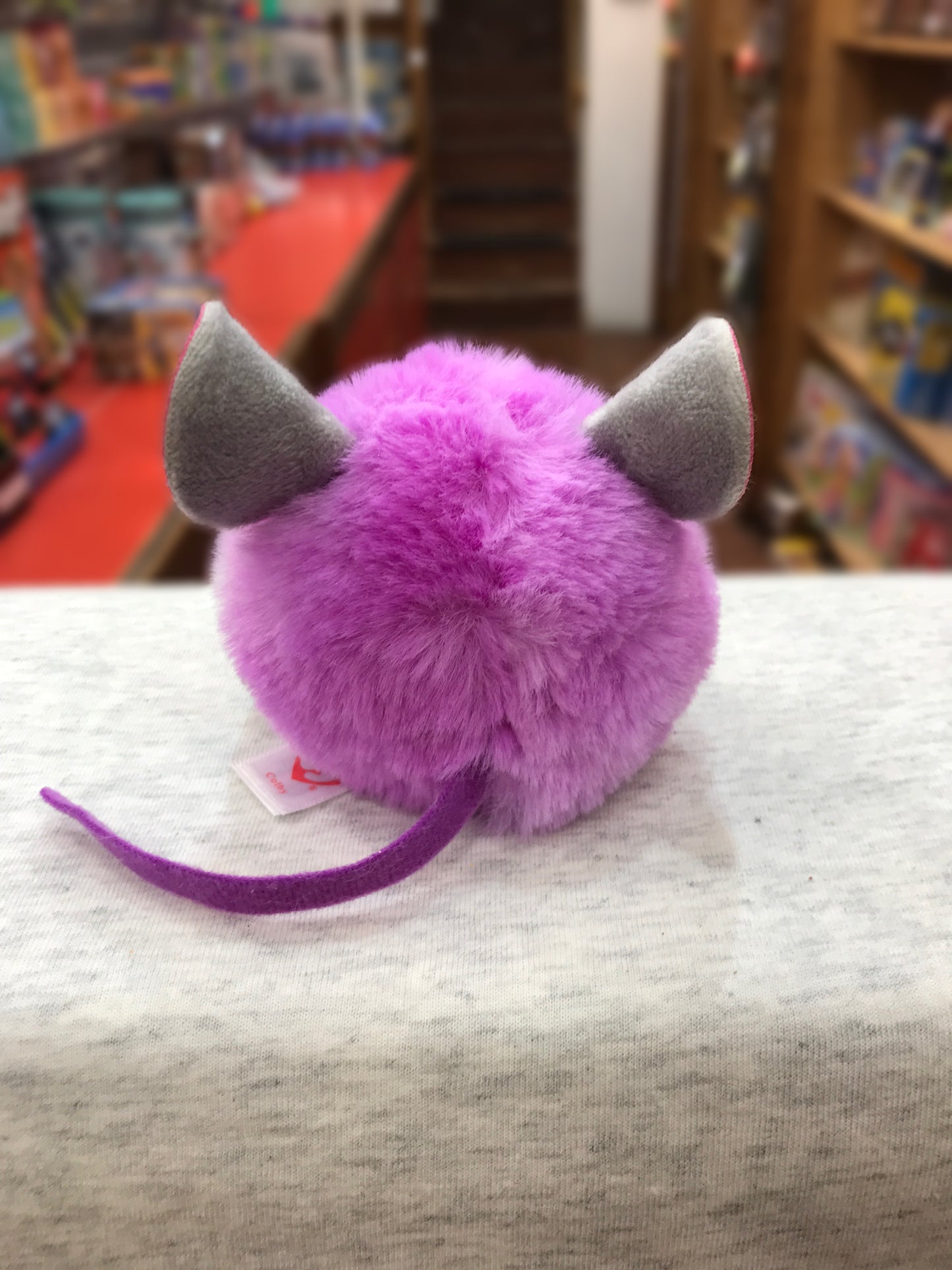 Ty Puffies Colby purple mouse plush toy with gray ears and long tail, displayed in toy store setting