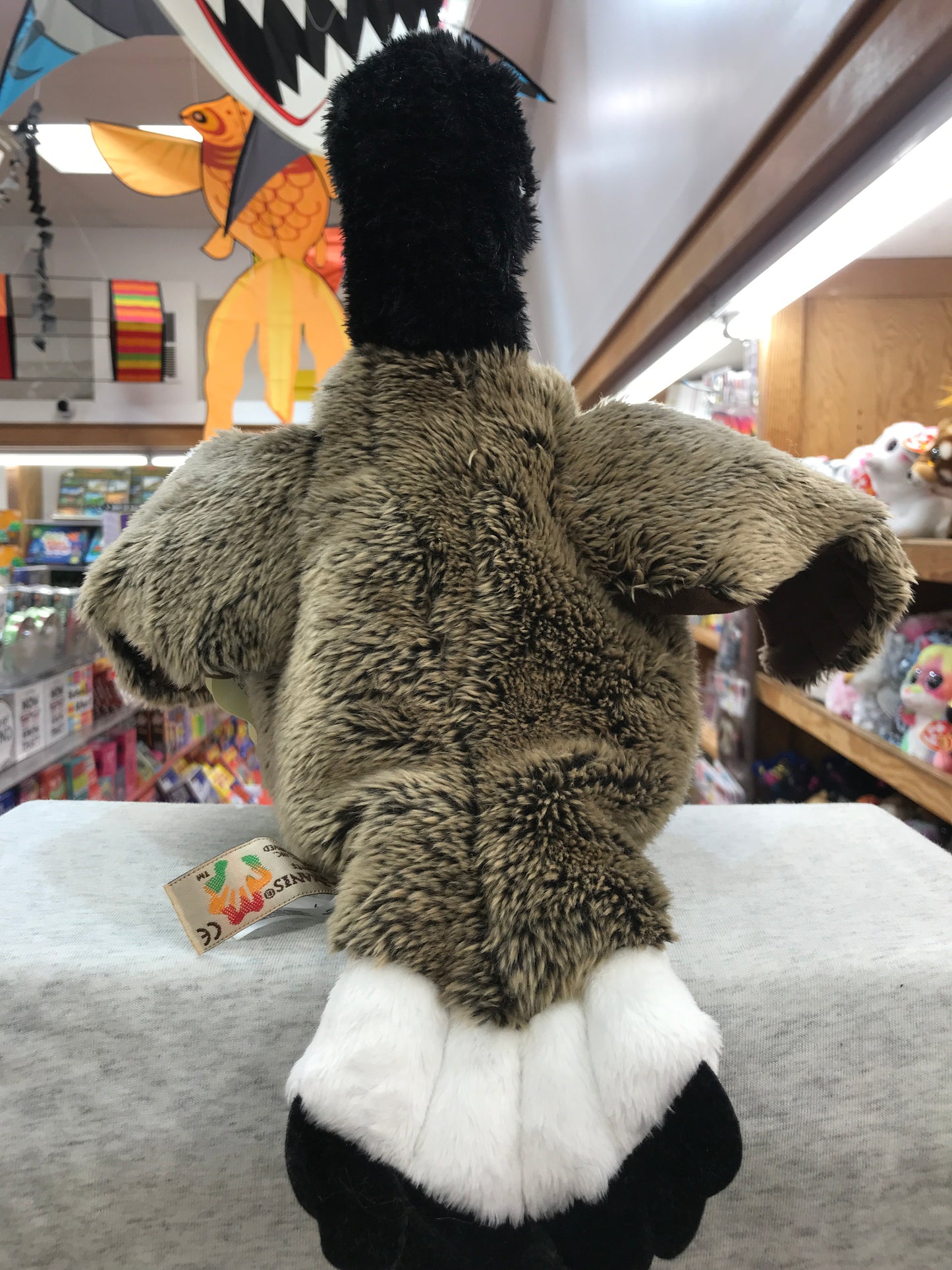 Folkmanis Canada Goose puppet with movable wings in toy store, surrounded by colorful toys and shelves