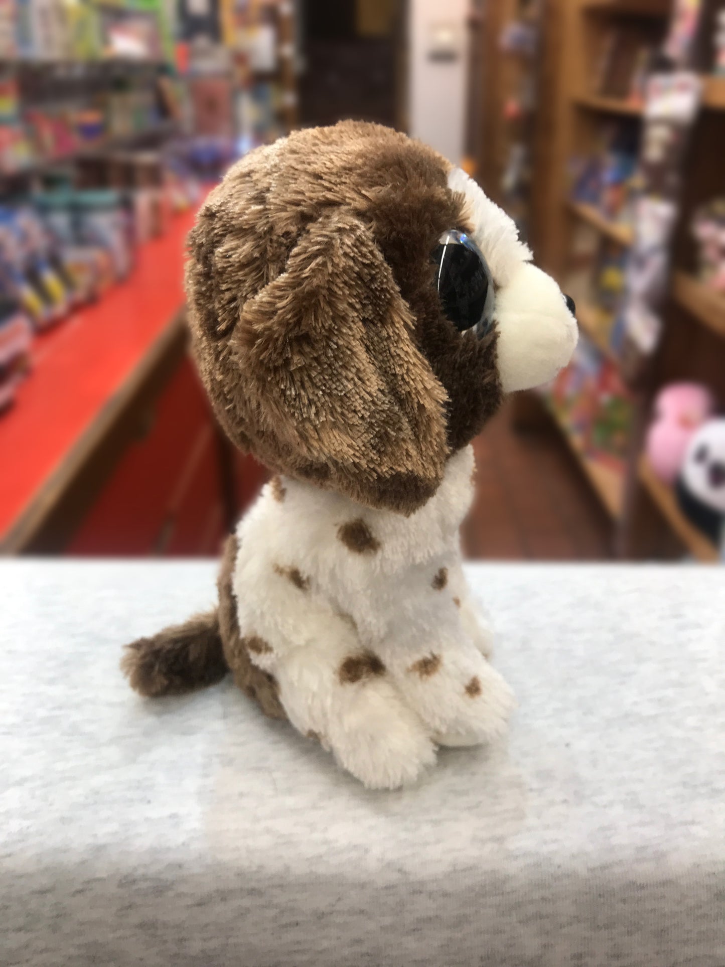 Ty Beanie Boo Muddles plush dog with brown and white spotted fur, sitting on display in toy store