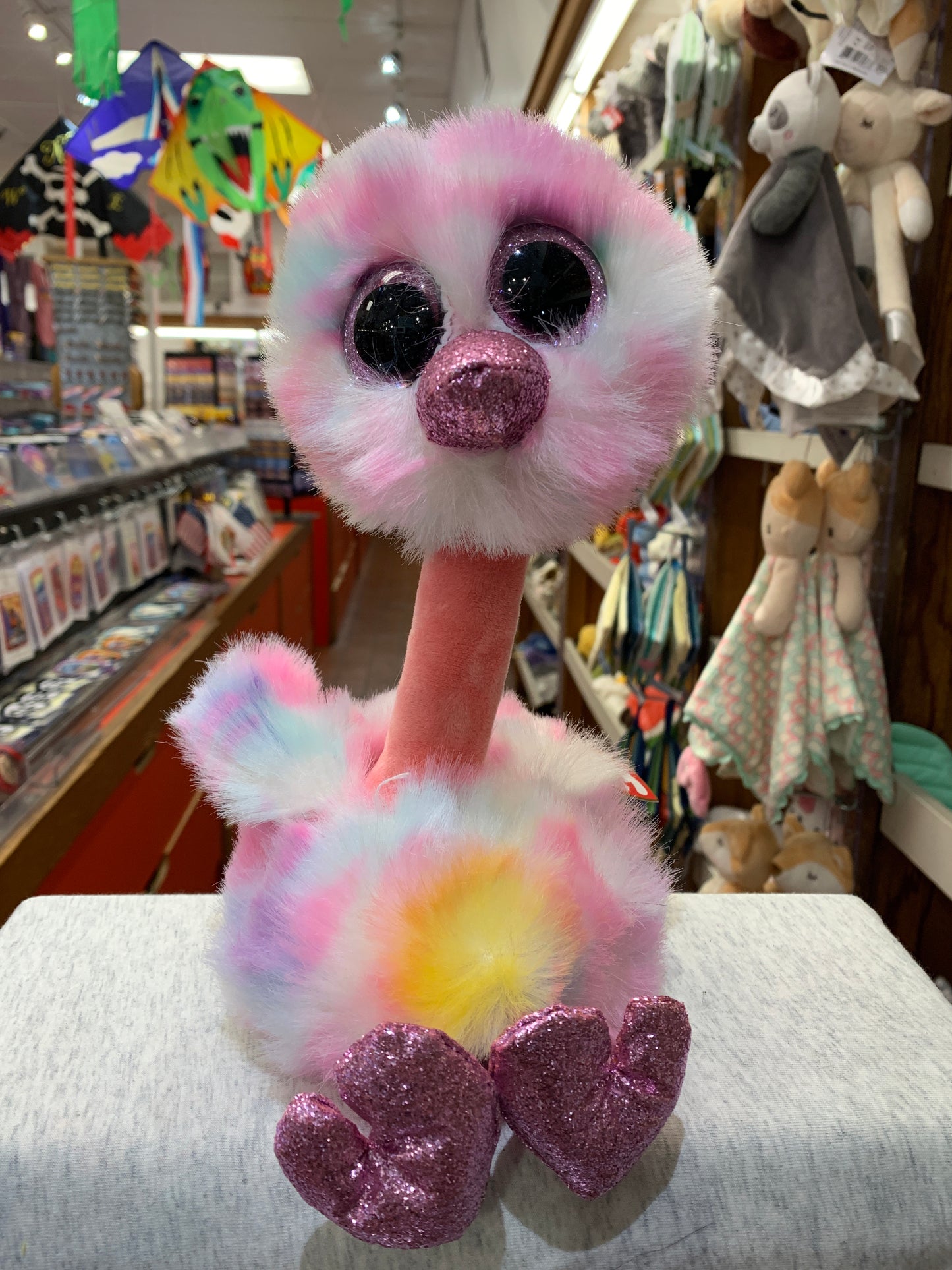 Ty Beanie Boo Avery, pastel pink ostrich plush with sparkly eyes and glittery feet, displayed in toy store