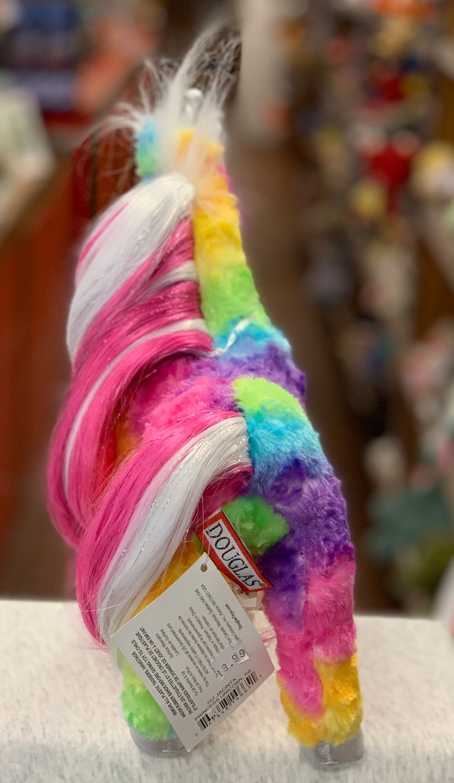 Rainbow unicorn plush toy with vibrant colors, pink and white mane, and Douglas brand tag, perfect for imaginative play