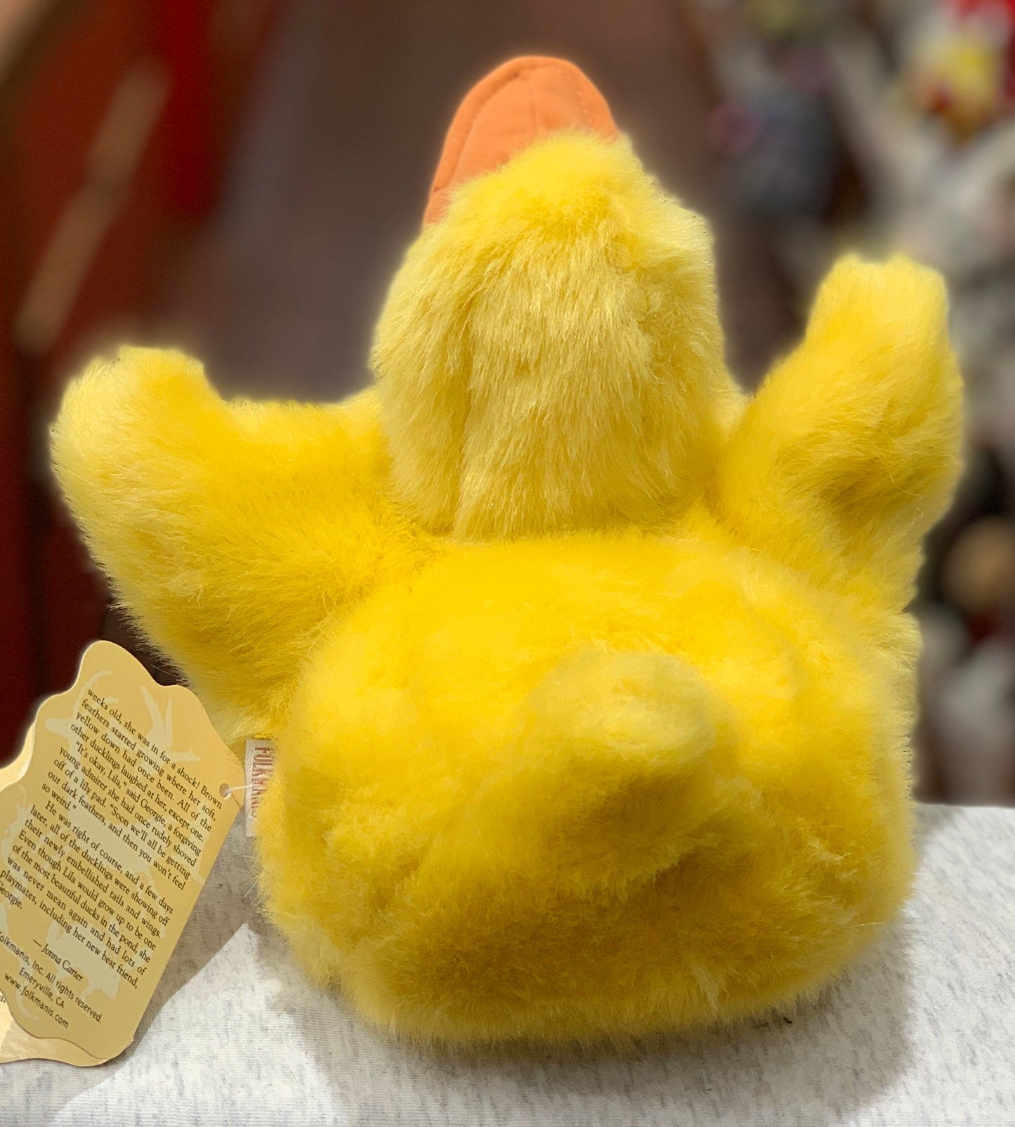 Fluffy yellow 9-inch Folkmanis duckling puppet with movable beak and wings, shown from behind with product tag