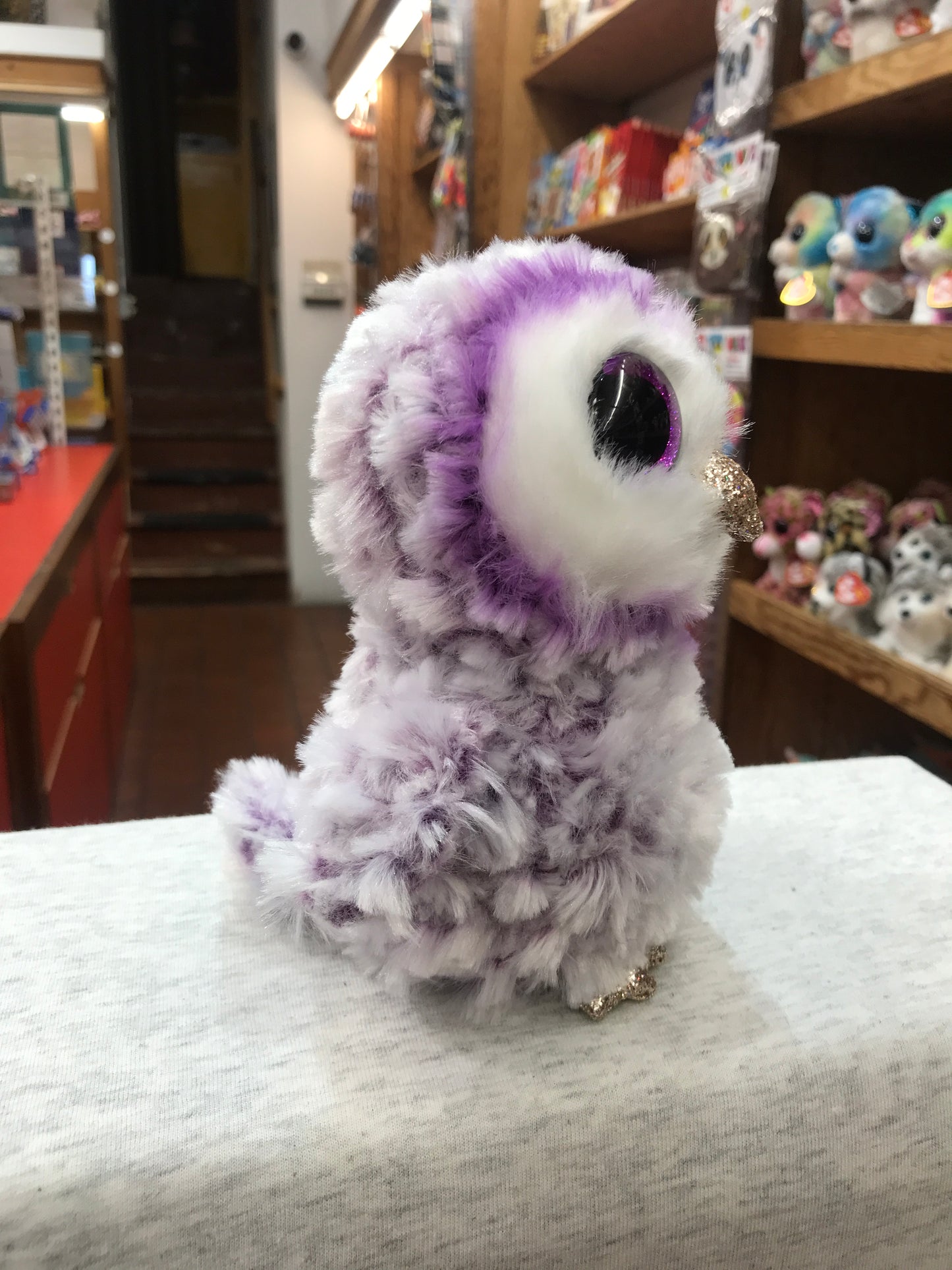 Ty Beanie Boo Moonlight purple owl plush with glittery feet and beak, large sparkling eyes, displayed in toy store