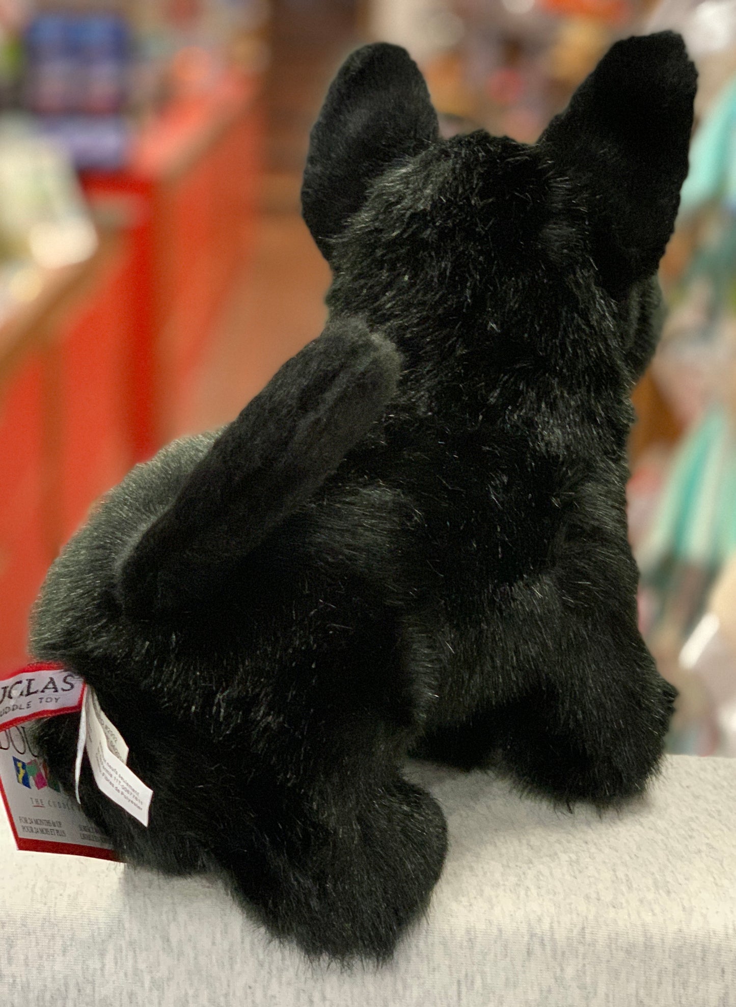 Plush black Scottie dog stuffed animal with distinctive terrier features, sitting on display with Douglas toy tag visible