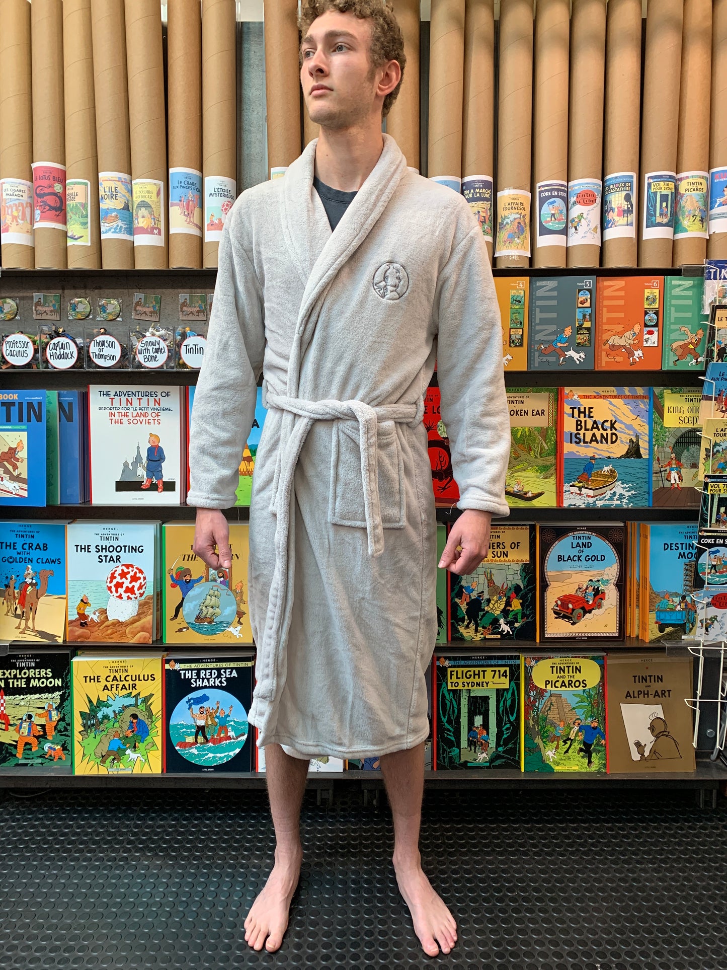 Grey Tintin robe on model surrounded by Tintin books and merchandise, showcasing comfort and fan appeal