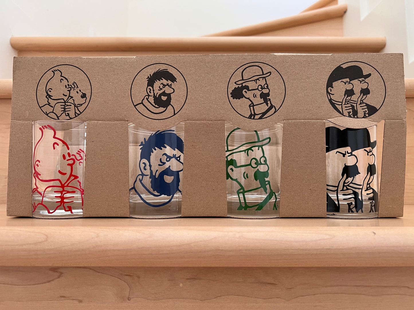 Tintin character glass tumblers set featuring four iconic figures in colorful designs, packaged in cardboard box with matching illustrations