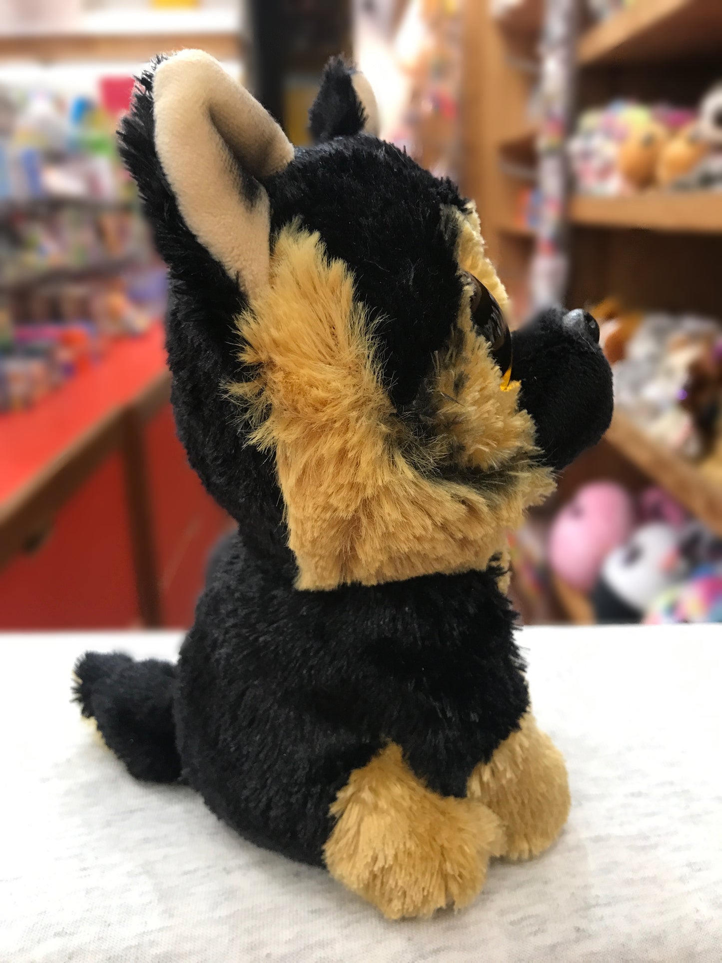 Ty Beanie Boo Spirit German Shepherd plush toy sitting on display, black and tan fur, large eyes, in toy store setting