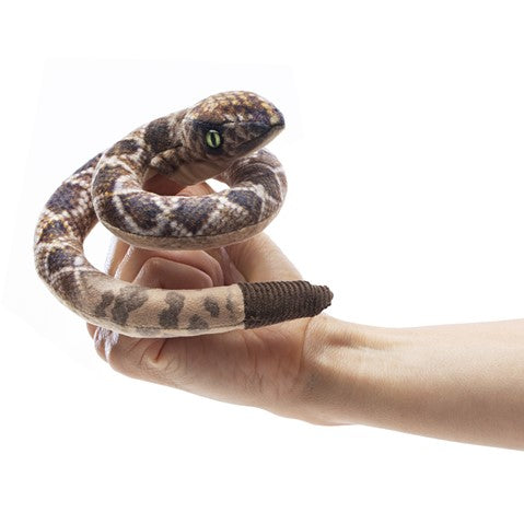 Realistic Folkmanis mini rattlesnake finger puppet with printed scales and rattle, coiled on a hand