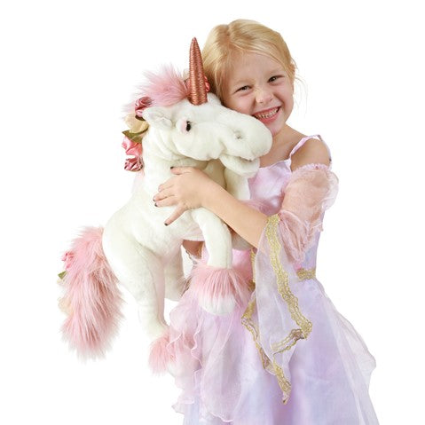 White unicorn puppet with pink mane and golden horn held by smiling child in princess dress
