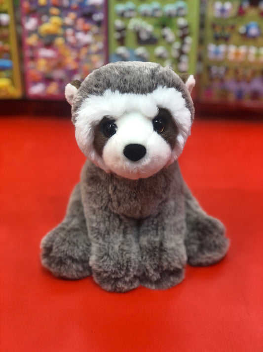 Adorable Douglas Mini Rudie soft raccoon plush toy with distinctive mask, sitting on red surface against colorful background