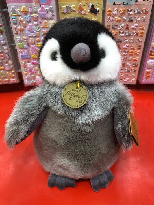 Adorable Aurora Miyoni Tots Emperor Penguin Chick plush toy with fluffy gray feathers and distinctive facial markings on red display