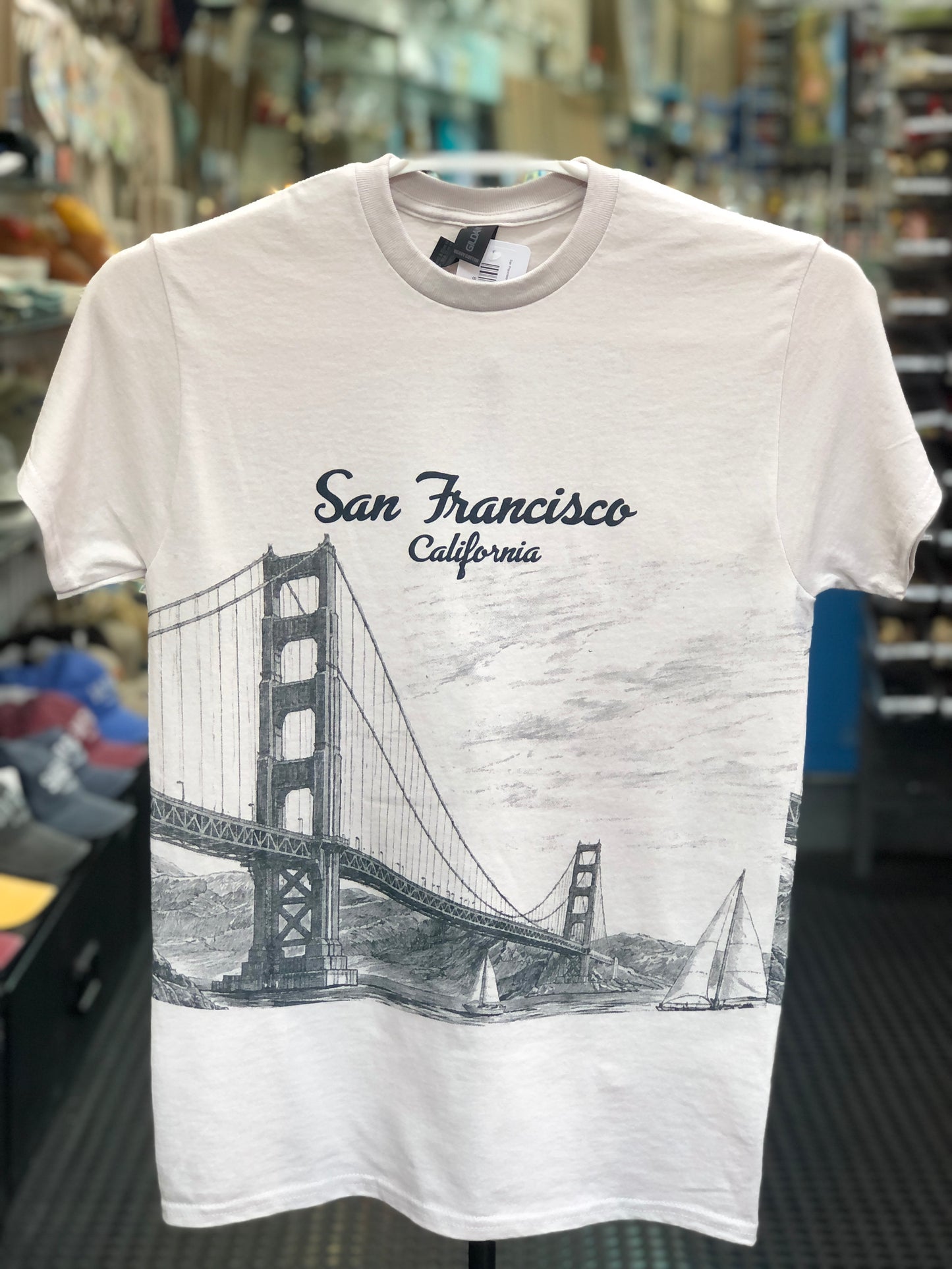 Ice-grey color t-shirt with Golden Gate Bridge graphic and 'San Francisco, California' text in a store setting.