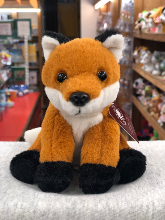 Soft, cuddly Charlie Bears fox plush toy for babies, with orange fur and black paws, displayed in a toy store