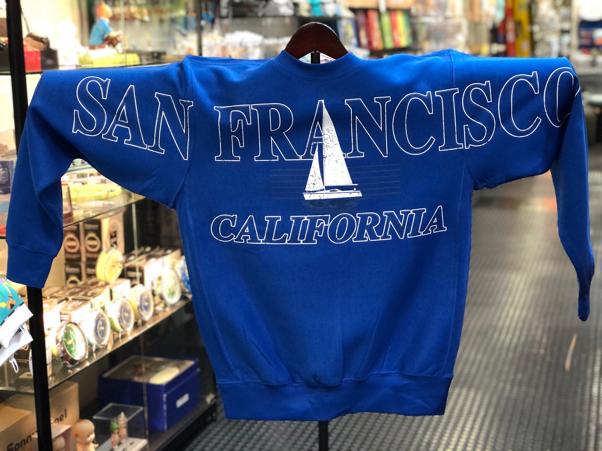 Blue sweatshirt with 'San Francisco California' text across the chest and arms and sailboat graphic.