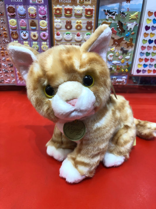 Adorable Miyoni Tots orange tabby kitten plush with realistic features, sitting on red surface with colorful stickers in background