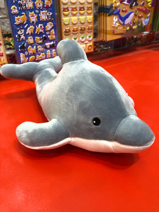 Soft, squishable Mary Meyer Smootheez dolphin plush toy on red display with colorful animal stickers in background