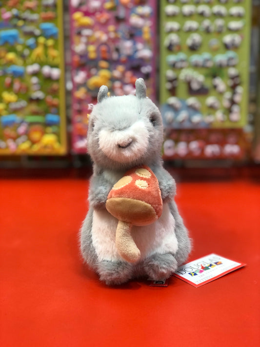 Cute Douglas squirrel plush toy holding spotted mushroom, colorful toy display background, autumn-themed stuffed animal