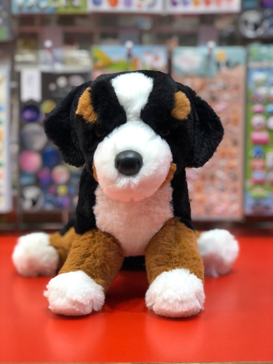 Soft Bernese Mountain Dog plush toy sitting on red surface, realistic features, floppy design for playful posing