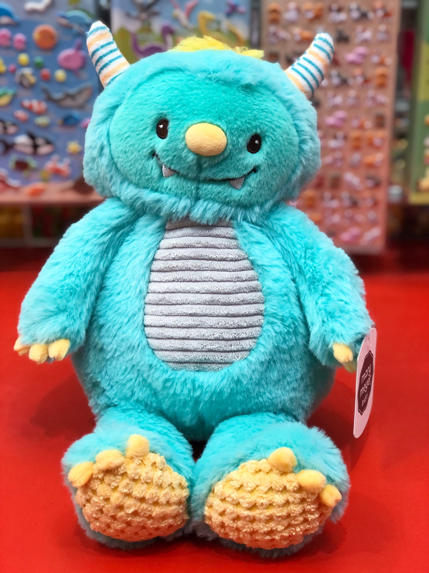 Blue plush toy with yellow accents on a red surface