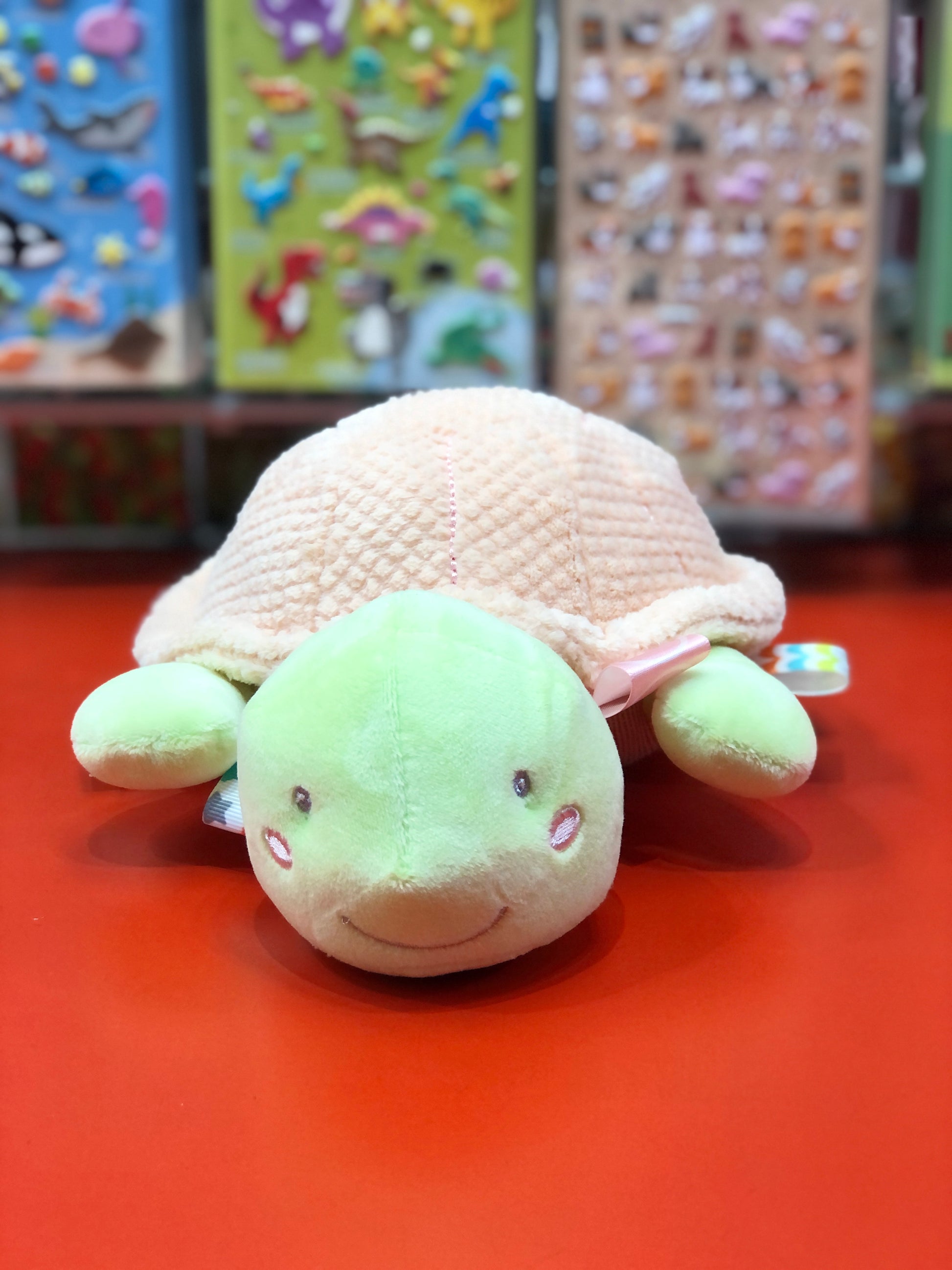 Plush turtle toy on a red surface with colorful background