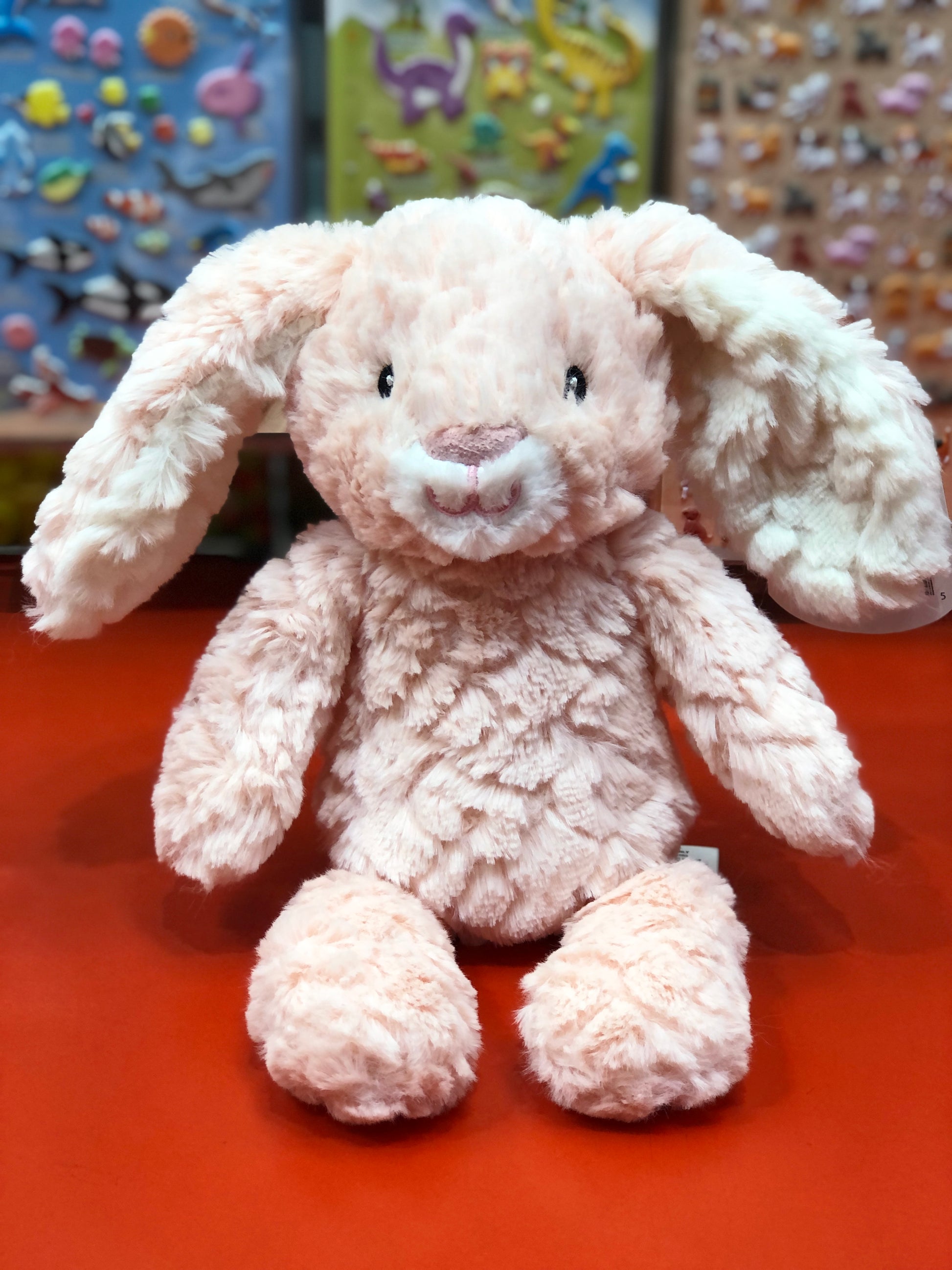 Plush bunny toy on a red surface with colorful background