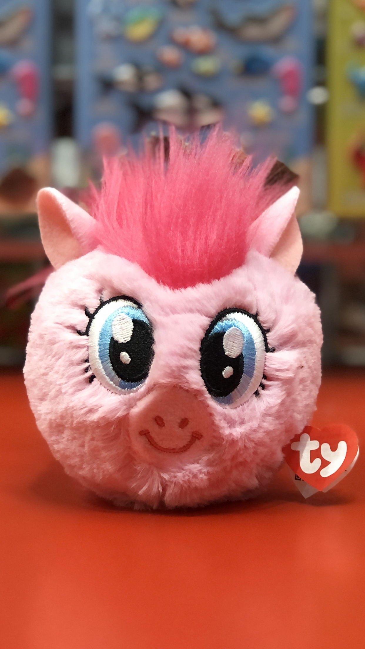 Pink plush toy with a mohawk on a red surface, featuring the Ty brand.