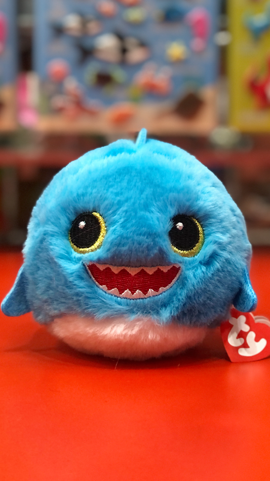 Blue Ty plush toy with a happy expression on a red surface