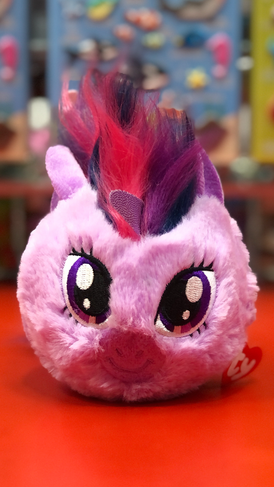 Pink Ty plush toy with purple and red hair on a colorful background.