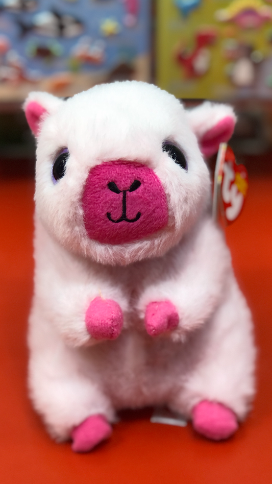 Smiling Ty pink capybara plush sitting on a red counter. 