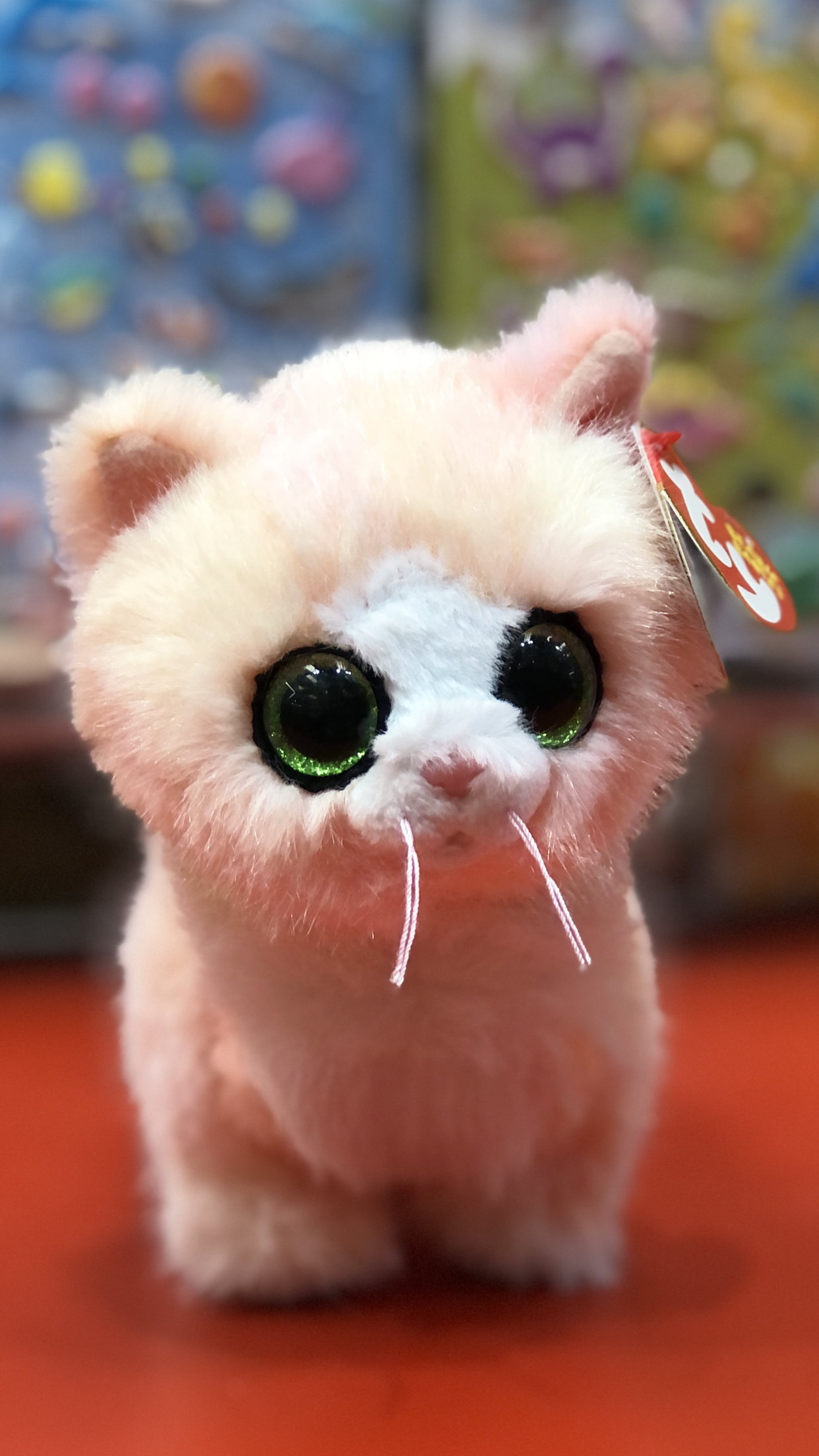 Ty plush toy cat with green eyes on a colorful background.