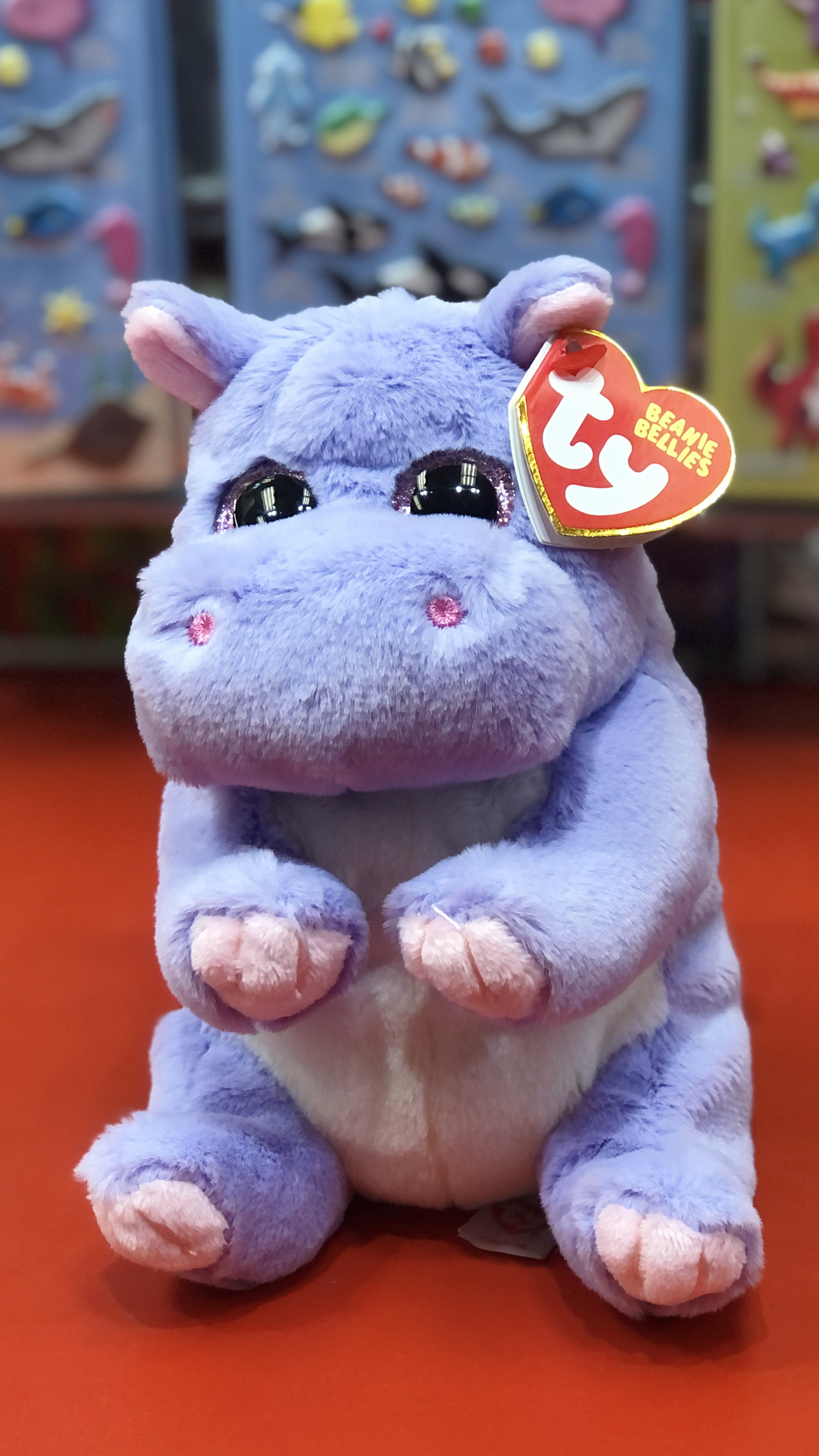 Ty purple plush hippo with a visible brand tag on a red surface. 