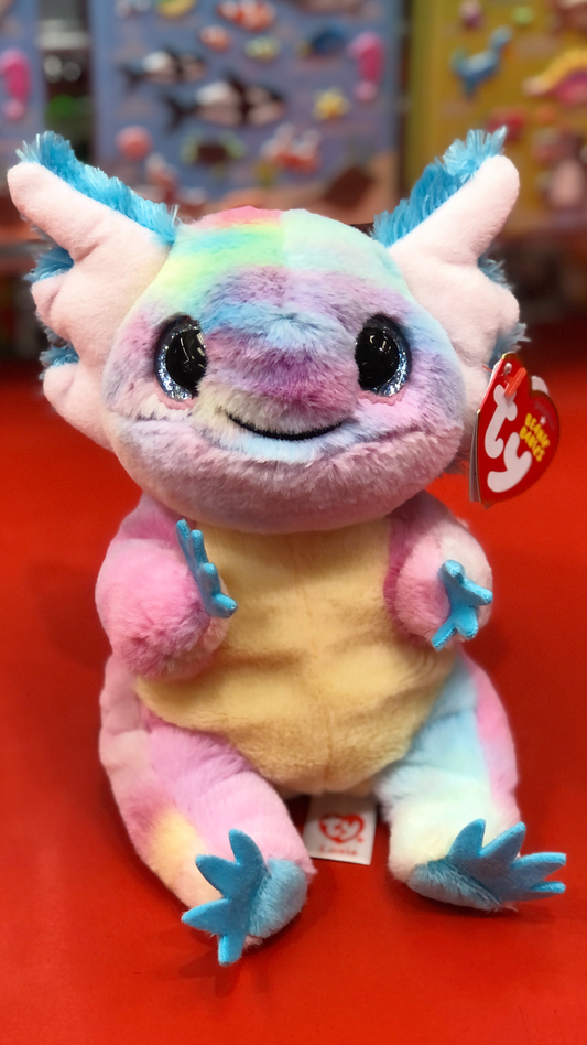 Ty beanie babies style rainbow axolotl plush with a smiling face on a red surface.