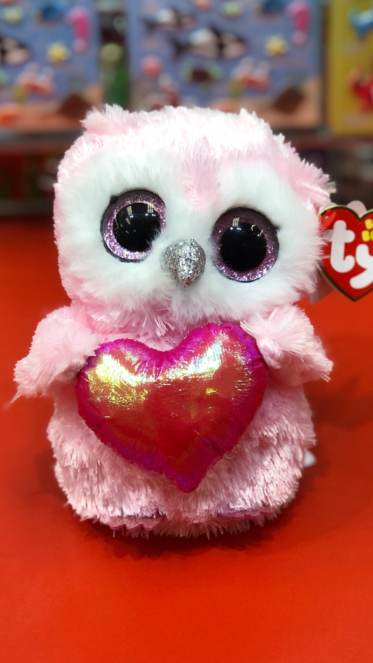 Ty pink and white owl plush holding a red heart on a red background.