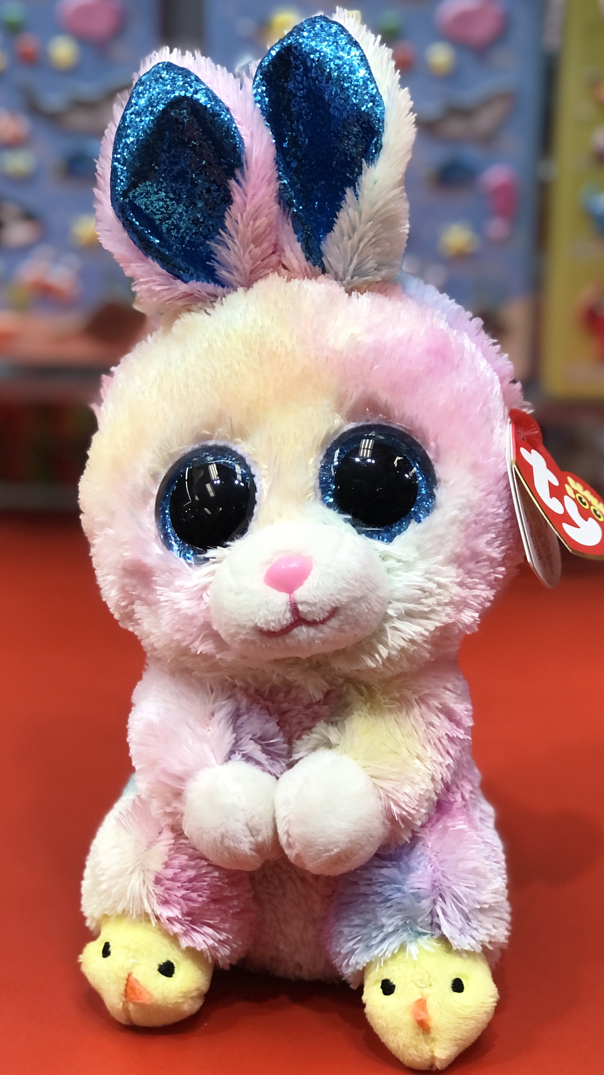Ty plush toy with blue and pink colors on a red background