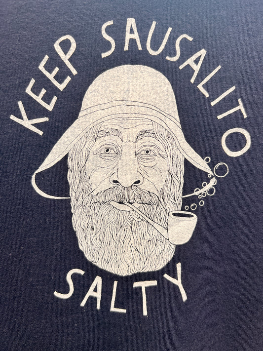 Toddler-sized navy blue t-shirt featuring a white graphic of a bearded sailor in a rain hat with 'Keep Sausalito Salty' text and a bubble pipe blowing bubbles.