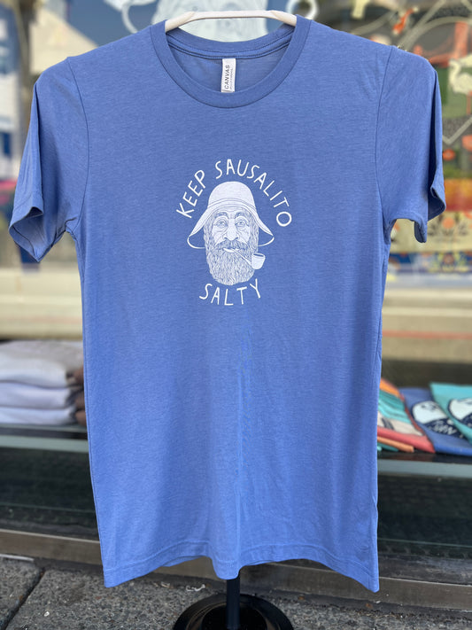 A heather blue short sleeve t-shirt featuring a white circular graphic of a bearded fisherman in a  sou'wester rain hat with a pipe, surrounded by the text "Keep Sausalito Salty."