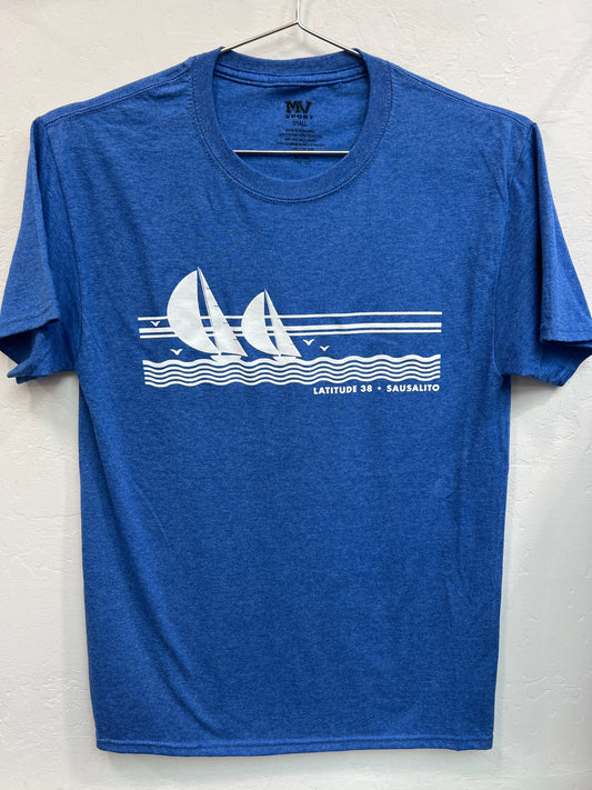 A heather blue crewneck t-shirt hanging on a wire hanger against a white textured wall. The shirt features a white screen-printed graphic across the chest depicting two sailboats with full spinnakers sailing on stylized ocean waves under a three-line horizon, accompanied by the text "LATITUDE 38 • SAUSALITO" in a clean sans-serif font.