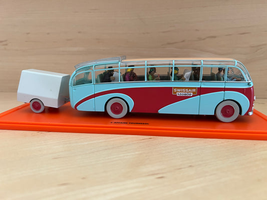 Model of a Swissair bus with a trailer on an orange stand against a wooden background