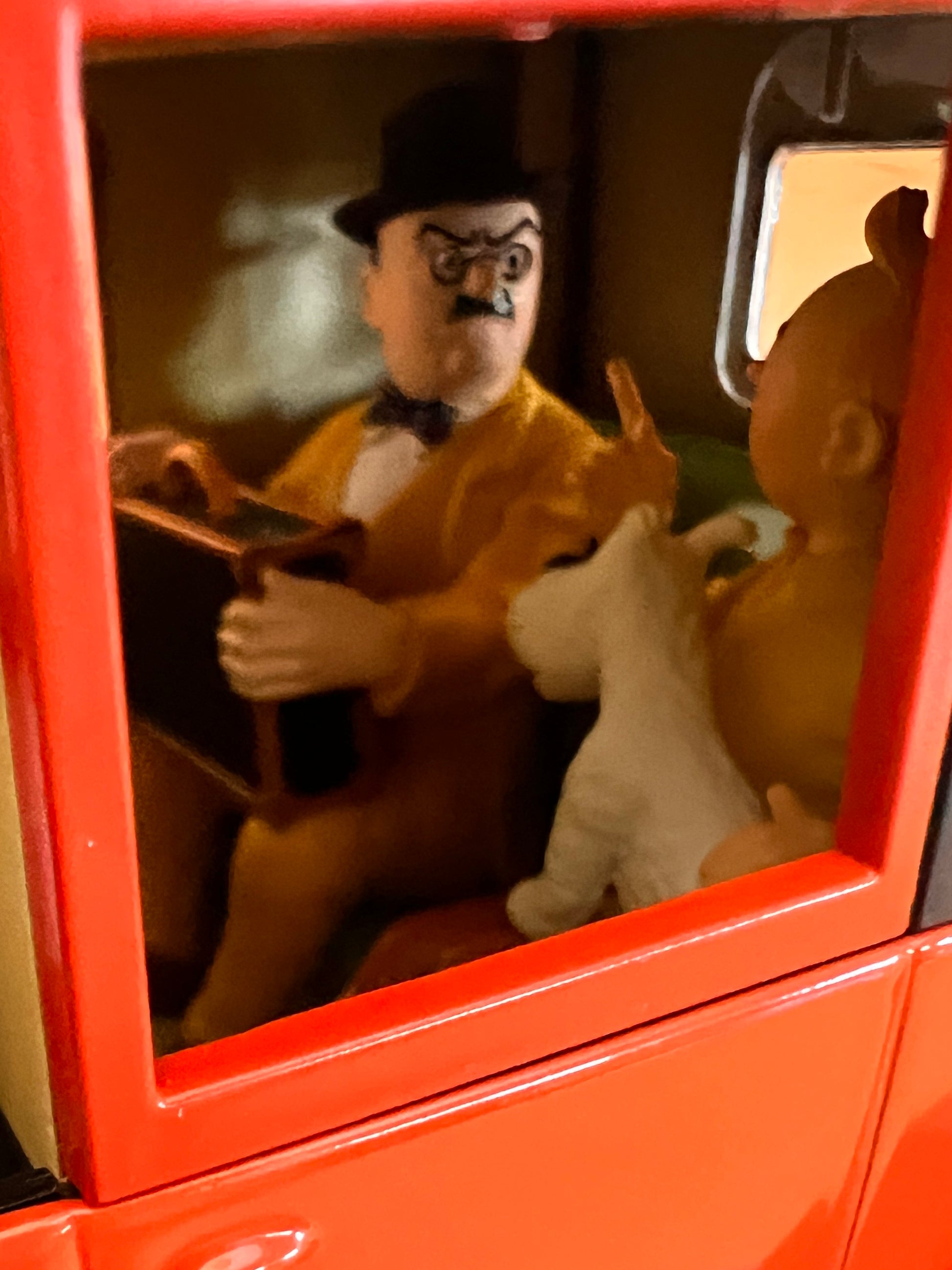 Tintin is in a desperate hurry to reach the Hotel Cornavin to find Professor Calculus. He jumps into the first available taxi, only to find it is already occupied by this man. To get the driver to prioritize his destination, Tintin famously pretends that Snowy has been bitten by a rabid dog and they must rush to the Pasteur Institute immediately. The figure captures the man's "frowning" and "clutching" pose perfectly, reflecting his annoyance and concern as the taxi speeds off with him still inside.