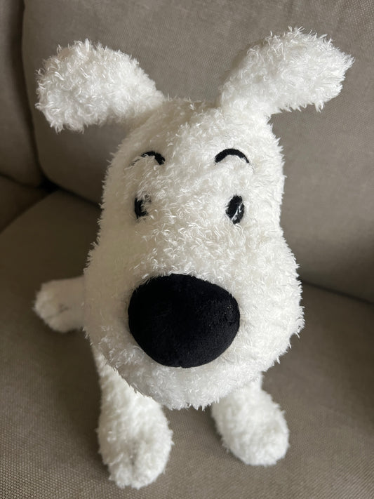 A close-up front view of a large, fluffy white plush Snowy dog sitting upright on a neutral beige cushion. The plush features classic stitched black arched eyebrows, small black eyes, a prominent soft black nose, and characteristic pointed ears.