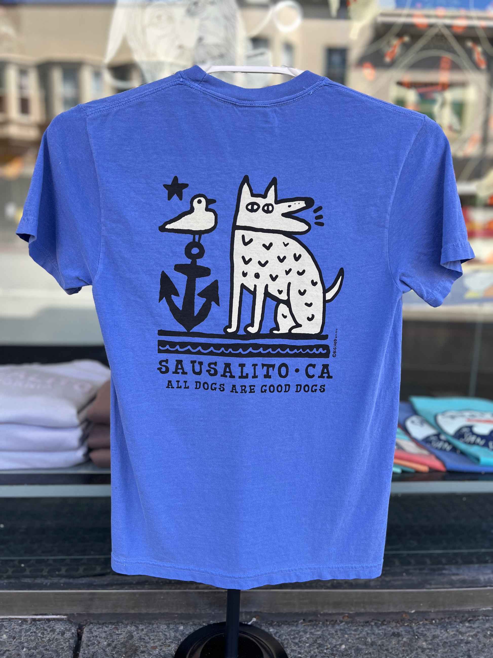 A bright "Flo Blue" short sleeve t-shirt featuring a graphic of a dog standing in front of a large anchor with "Sausalito, CA" and "Sausalito Ferry Co" printed below.